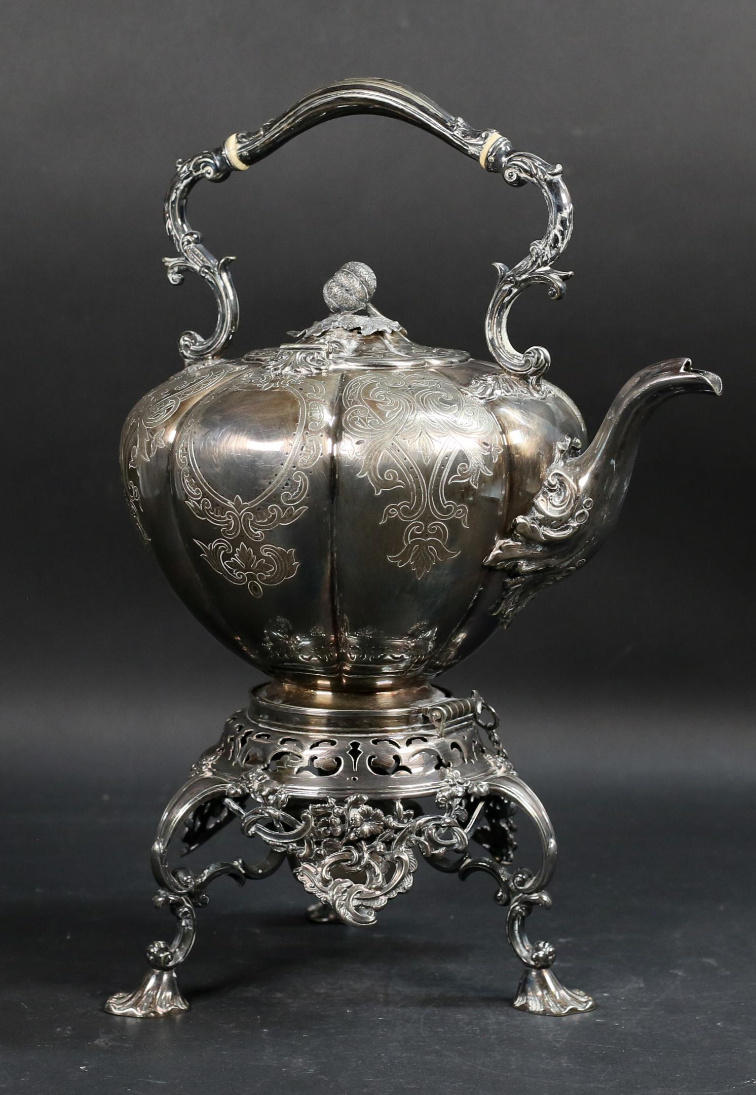 Sheffield English Silverplate Hot Water Kettle: English silverplate tilting hot water kettle on stand. William Hutton, Sheffield crossed arrows mark on underside of kettle. Engraved with scroll decoration, gourd finial on lid. 17"H to top of handle