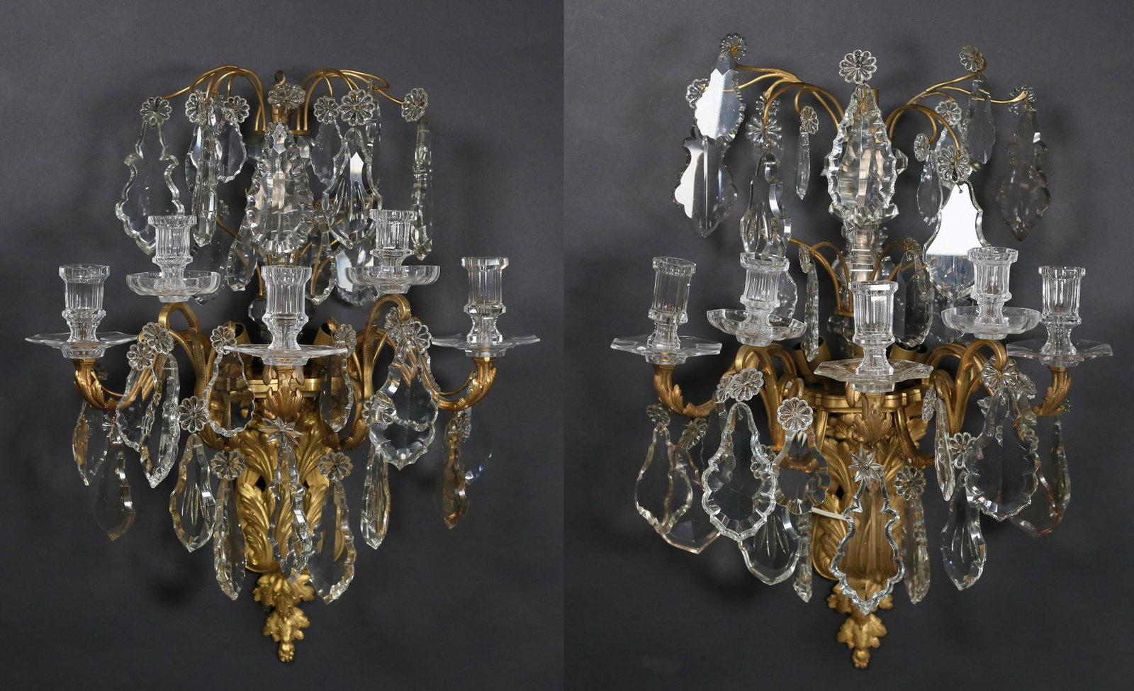 Pair Baccarat Style Gilt Bronze & Crystal Sconces: Pair of Louis XV style gilt bronze sconces. Baccarat style crystal drops and candle cups. Unsigned. Each 26 1/2"L. Some mismatched crystals. From the collection of a prominent Connecticut family.