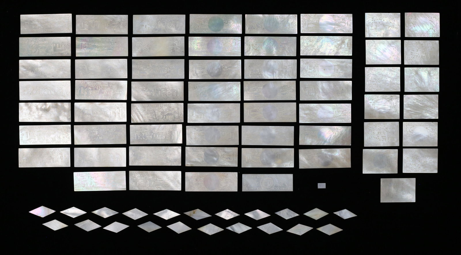 80 Mother-of-Pearl Chinese Loo Chips: 80 carved mother-of-pearl Chinese Loo chips / game tokens. Minor chips to edges. Rectangular chips 2 1/2"L. Minor chips and fleabites to the edges of 3 chips.