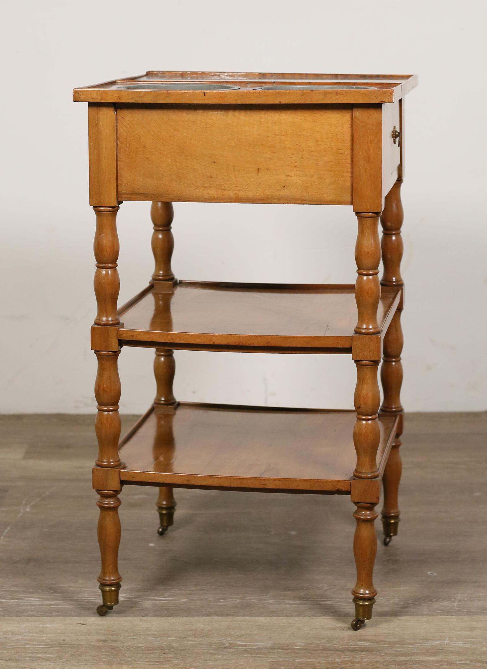 Louis Phillipe Style Rafraichissoir Bar Table: Louis Phillipe style rafraichissoir or bar table. 19th century. Walnut, turned legs on casters, two lower tiers, inset marble top, two removable metal wine or ice buckets. Separation to wood on one co