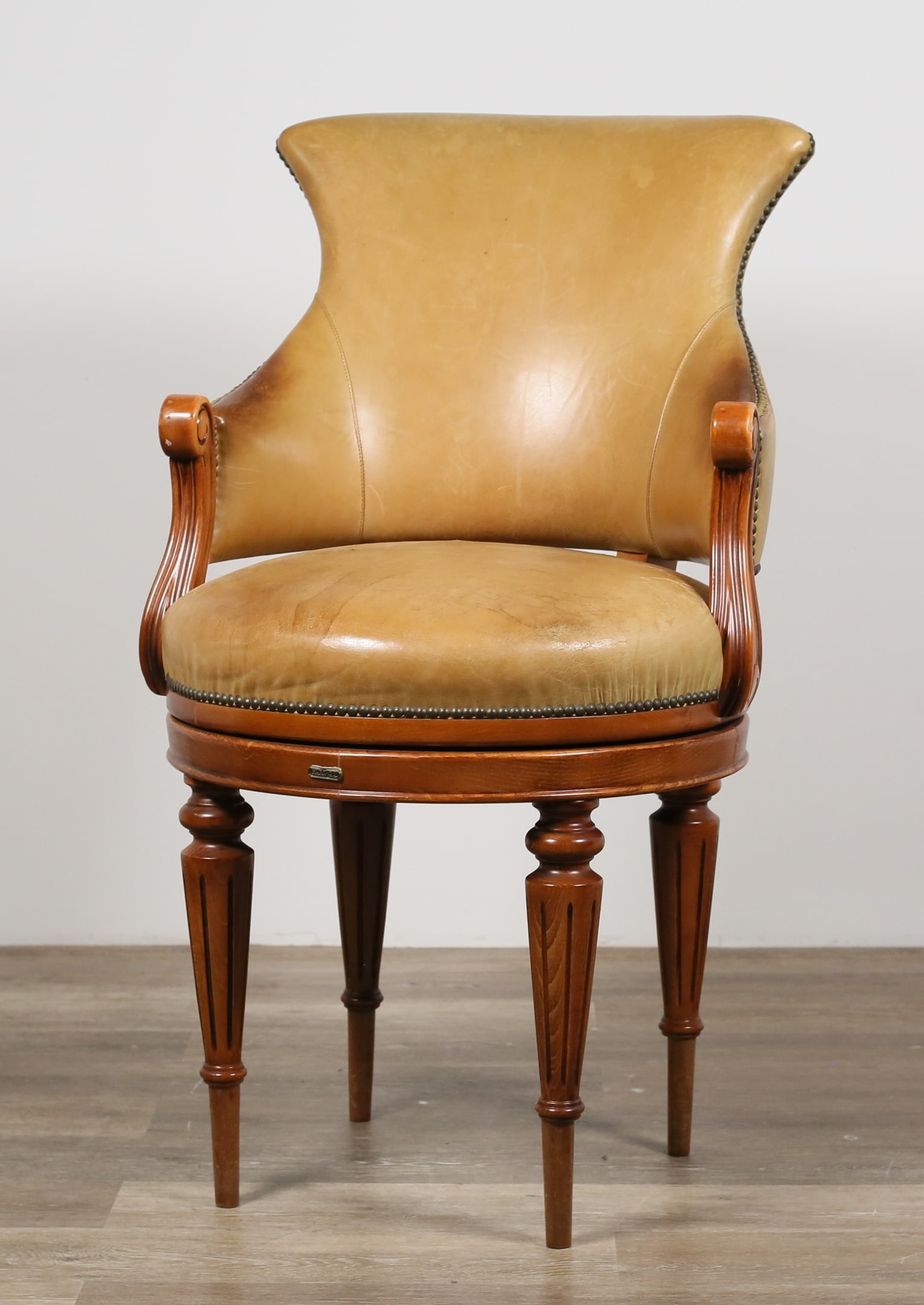 Louis XVI Style Swivel Chair by Hurtado: Louis XVI style swivel chair by Hurtado. Valencia, Spain, 21st century. Leather back and seating, nailhead trim, colonnade legs. Hurtado metal tag on one side of apron below seat. Wrinkling, cracking,