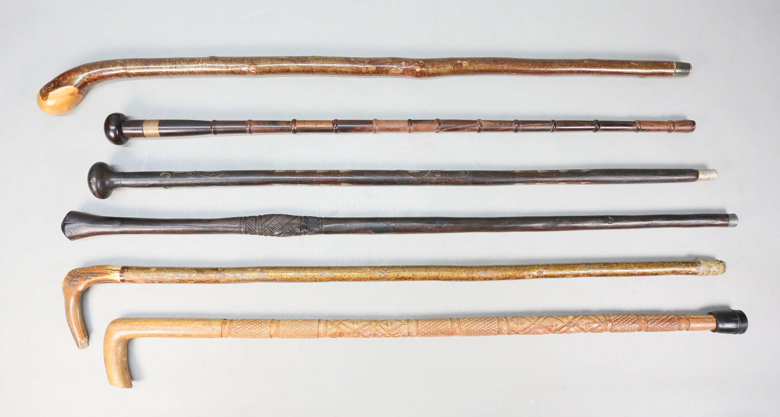 6 Carved Wood Canes & Walking Sticks: 6 carved wood canes / walking sticks. Longest 37"L. All with minor chips and scratches to wood, 1 with tape at ferrule.