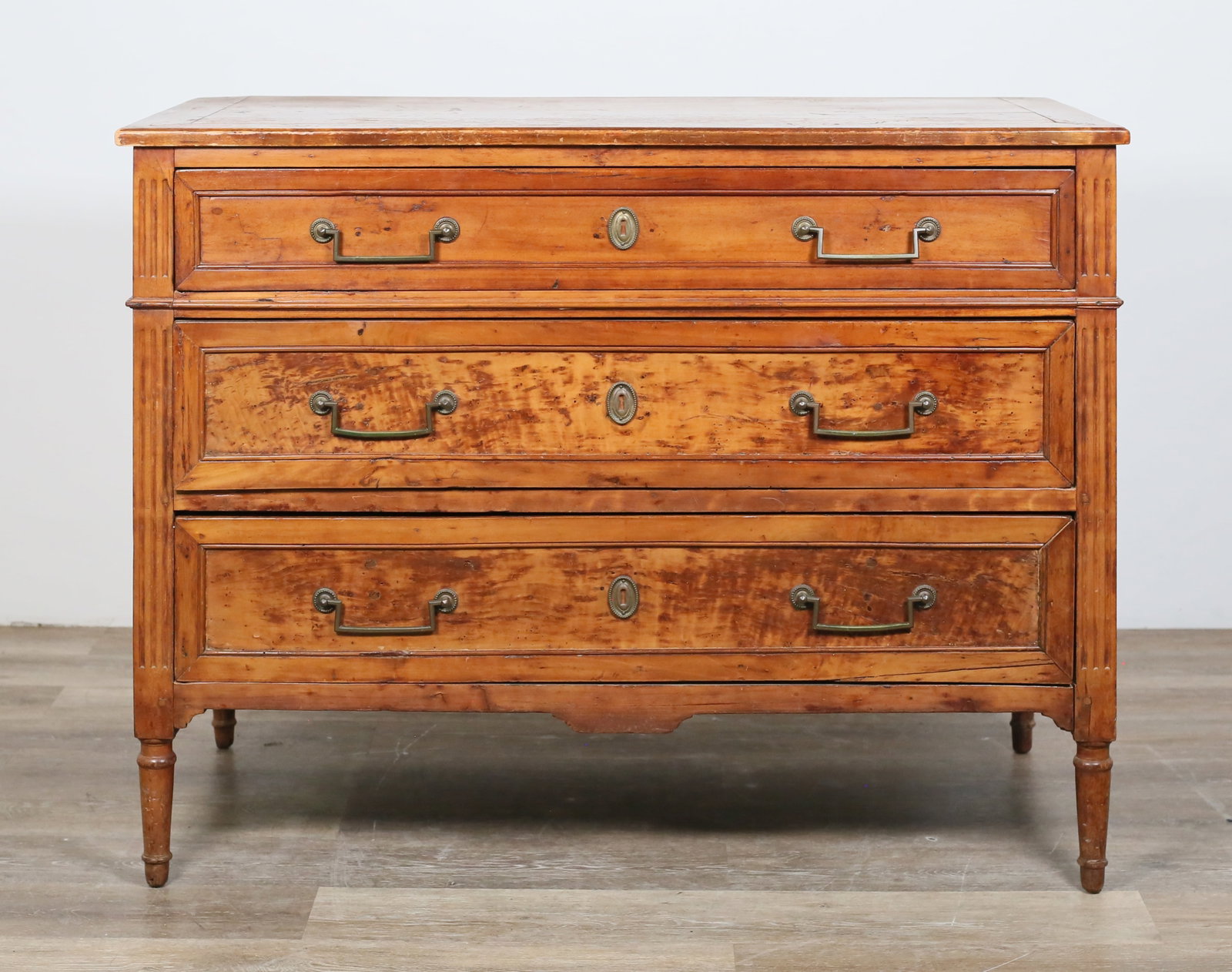 French Directoire Chest of Drawers: French Directoire chest of drawers. 19th century. Three dovetailed drawers, reeded sides and edges, later brass drawer pulls and escutcheons. Scuffs, chips, staining, water damage and wear throughout 