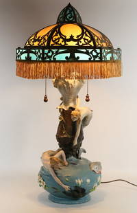 Art Nouveau Mermaid Slag Glass Lamp: Art nouveau figural lamp with a slag glass shade. Painted metal lamp base with mermaids, lobster and fish. With a caramel and blue hexagonal slag glass shade, with brass overlay and fringed rim. Lamp