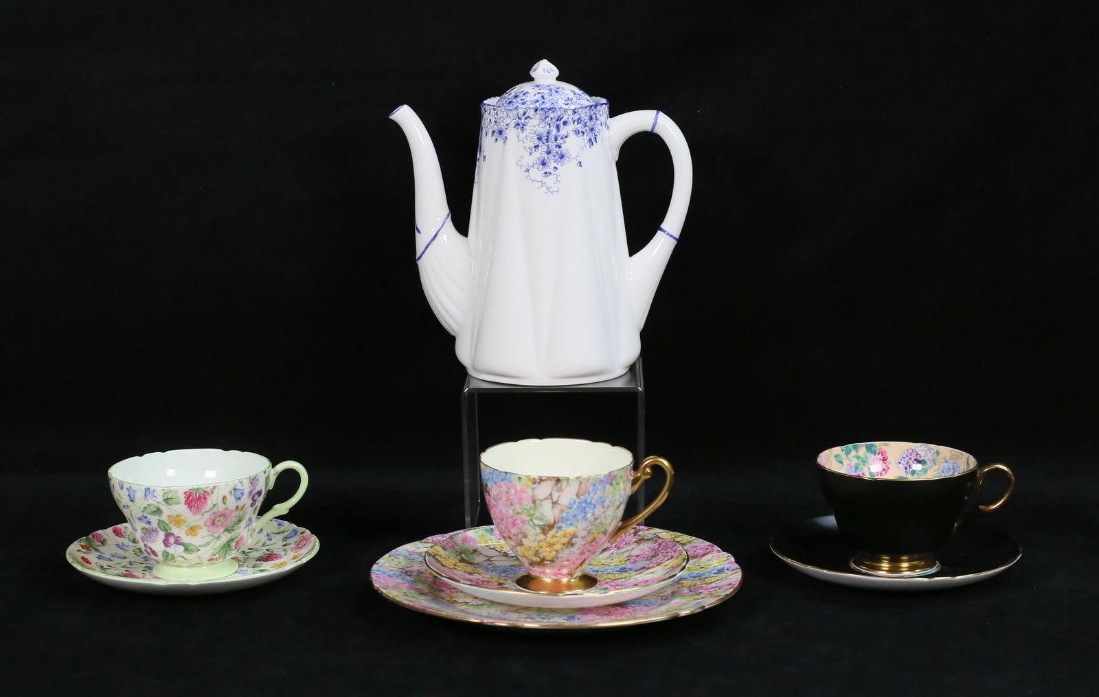 3 Shelley Chintz Cups & Saucers, Demitasse Pot: 8 pieces Shelley English bone china. Demitasse pot in the Dainty Blue pattern, 7 3/8"H; Rock Garden luncheon plate, cup and saucer, Country Side cup and saucer, black cup and saucer with Chintz interi