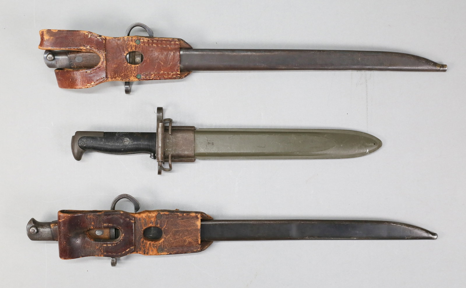3 WWII Era Bayonets Japanese & U.S.: 2 WWII-era bayonets. 2 Japanese bayonets with hooked quillons, Japanese Arsenal marks, metal scabbards and leather bayonet frogs, bayonets 19 7/8" and 20"L not including scabbards; U.S. UHF Garand rif