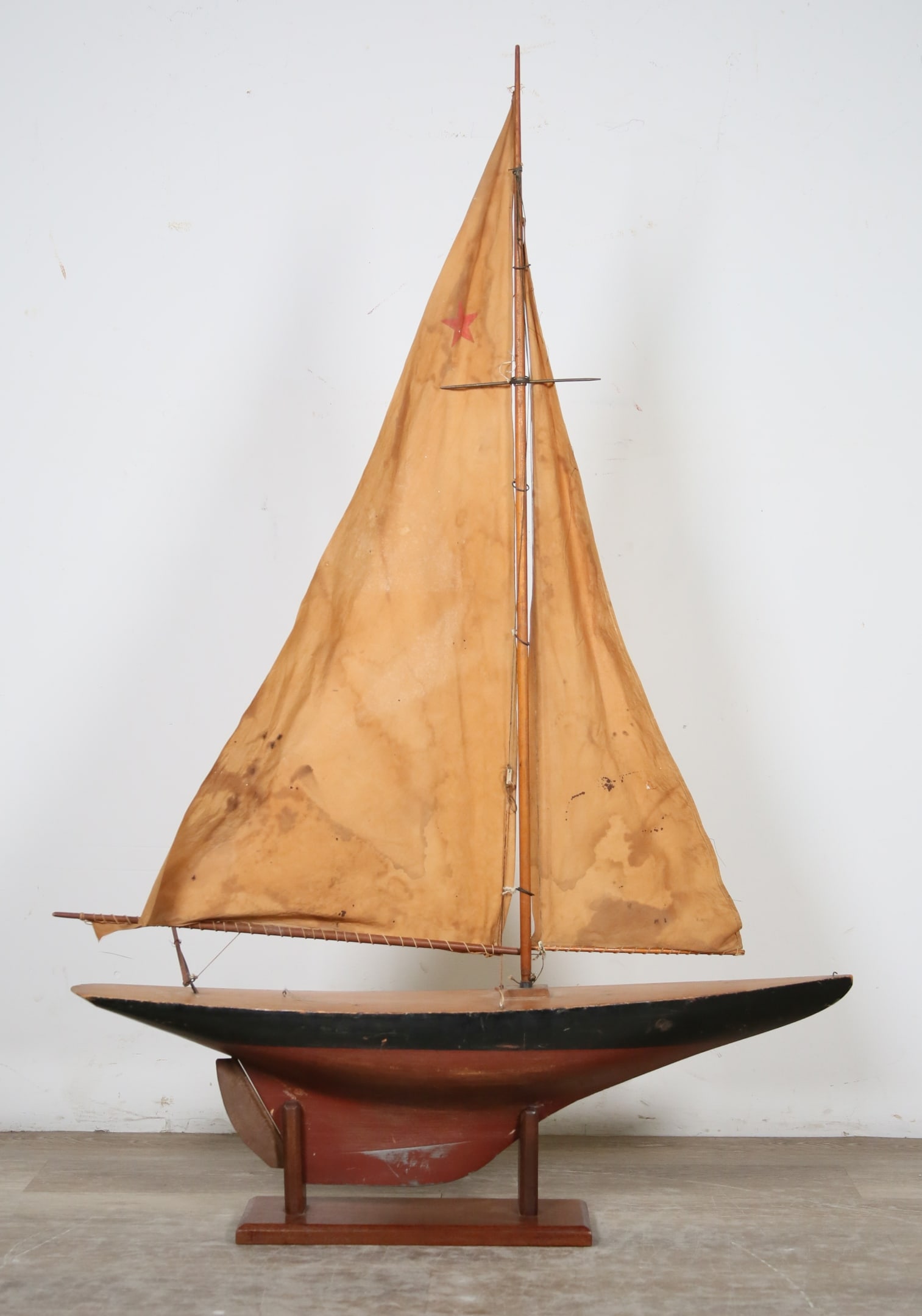 Wooden Pond Boat on Stand: Wooden pond sailboat with cloth shades, on wooden stand. Boat 31 1/2"L x 46"H including sails, without stand. Scratches, paint loss, repainting and minor chips to hull, split across deck, sails as is,