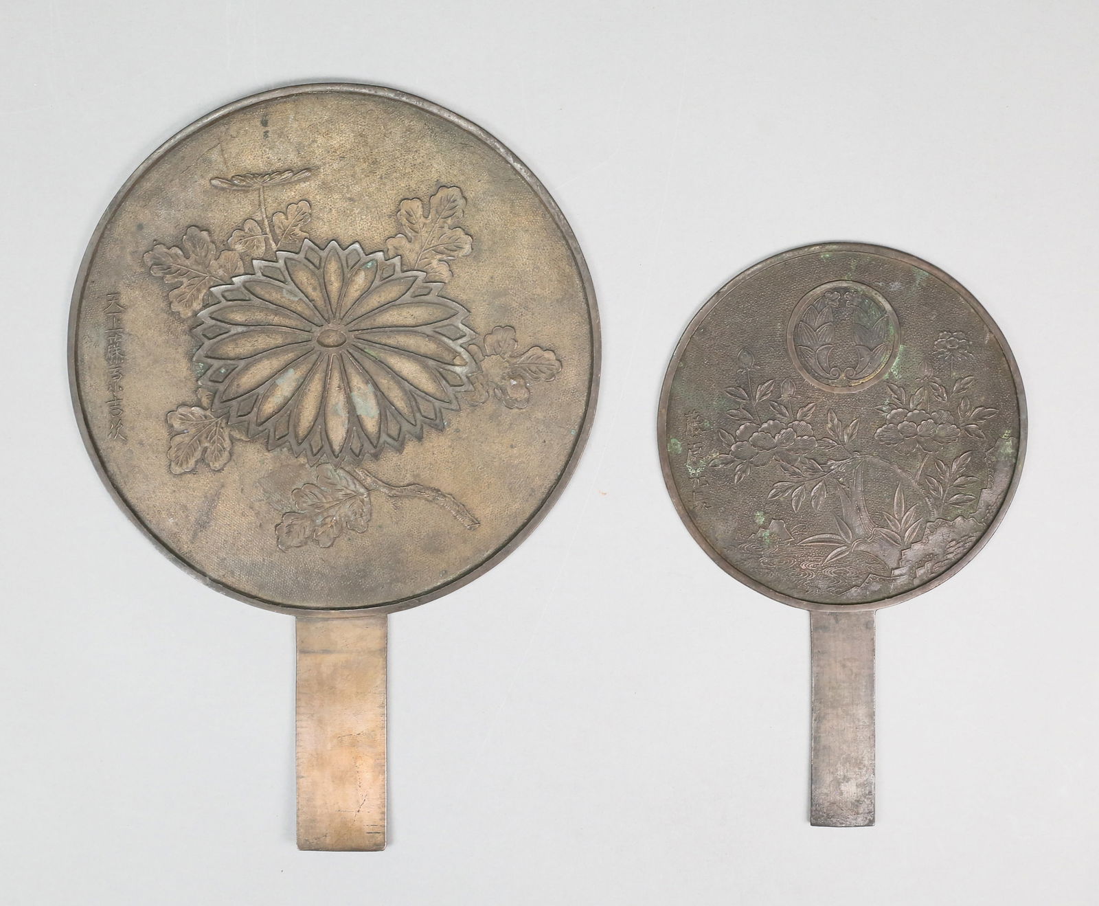 2 Japanese Bronze Mirrors: 2 Japanese bronze hand mirrors. Larger 11 3/4"L. Both with tarnishing, oxidation, scratches and losses to patina.