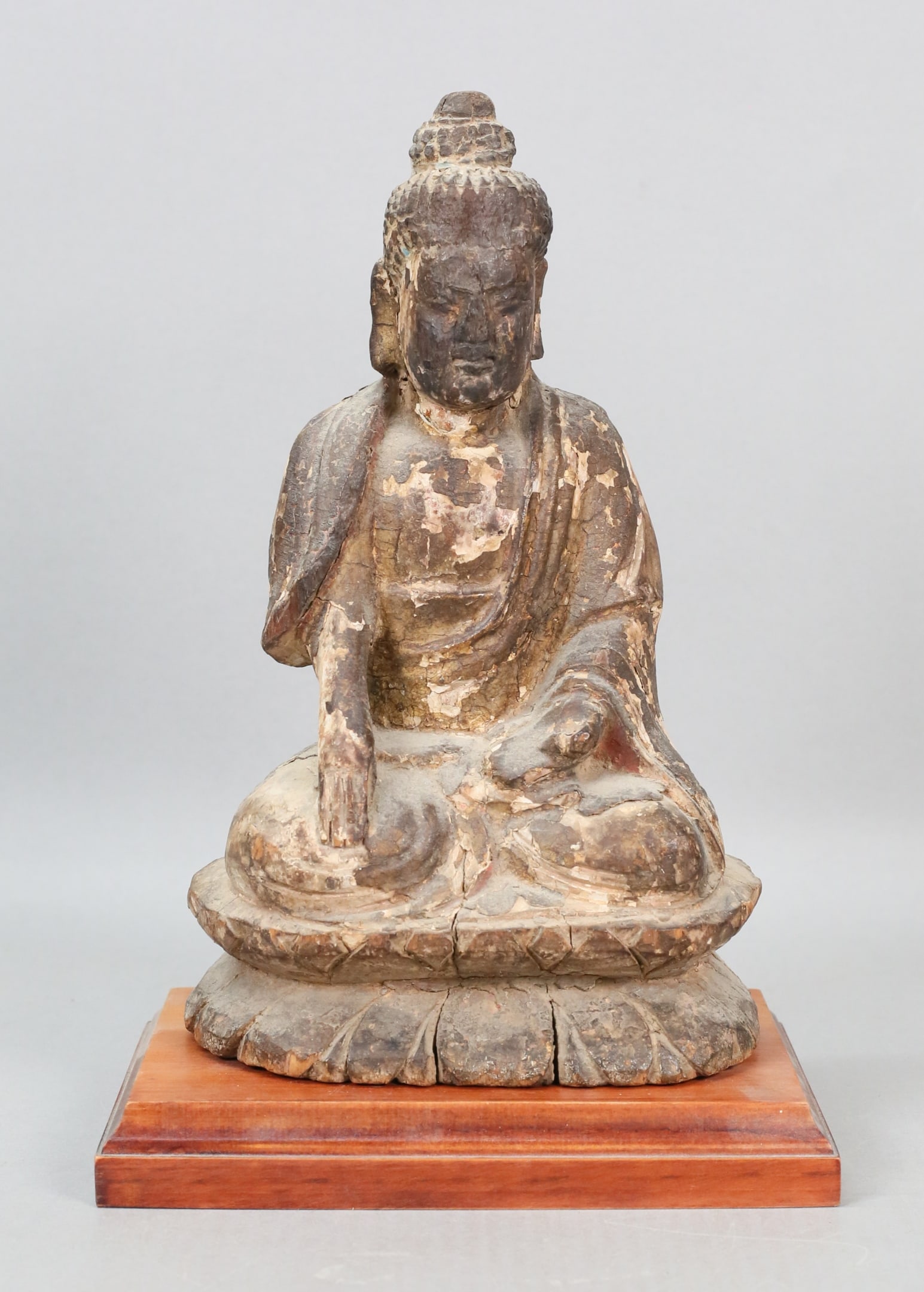 Carved Wood Buddha Figure: Carved wood Buddha statue. On a wooden stand. Figure 10"H without stand. Splits, chips, cracks and losses throughout.