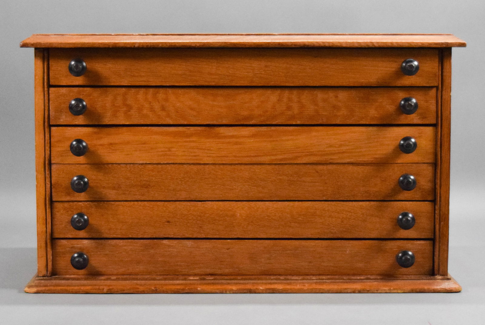 Oak Spool Cabinet: Oak spool cabinet. 6 drawers. 23"W x 11 5/8"D x 13 3/4"H. Chips to base, sides and throughout, scratches to top, divider in one drawer partially missing.