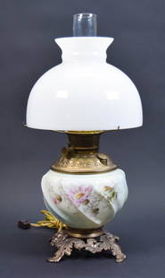 Wave Crest Electrified Kerosene Lamp: Wavecrest kerosene lamp. Opaque glass, floral motif, brass and gilt metal fittings and mounts, milk glass shade, electrified. Unsigned. 20"H with chimney and shade, lamp base 10 1/2"H. Dents to brass