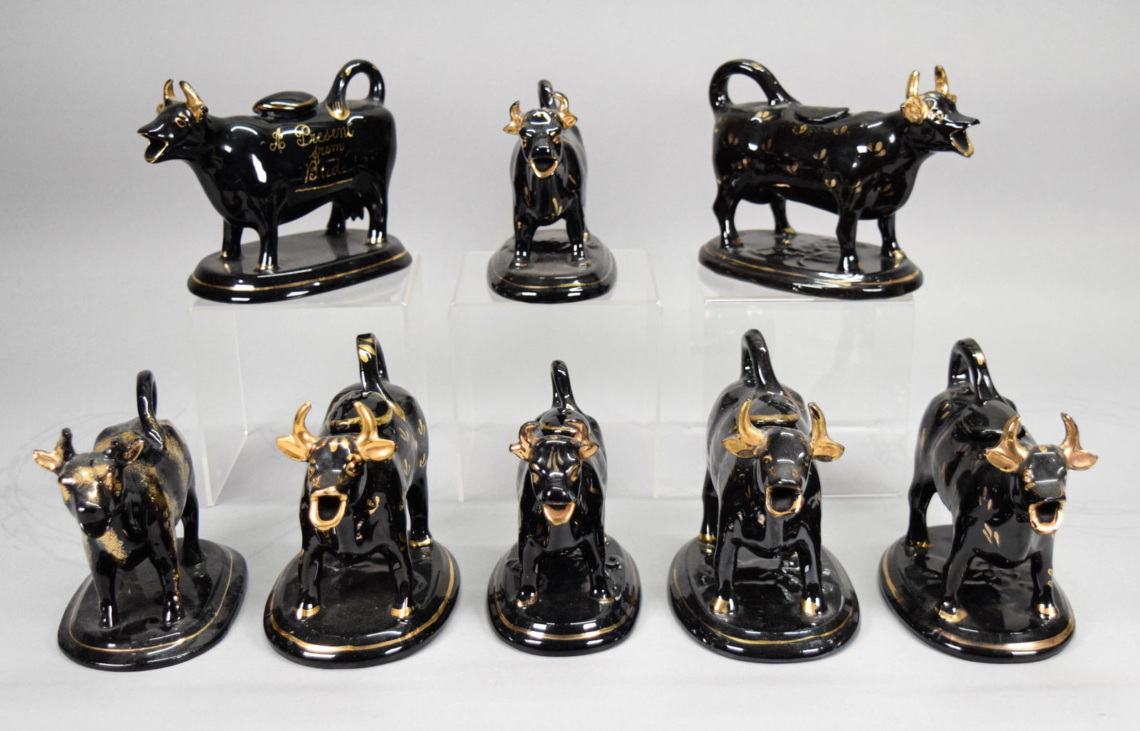 8 Jackfield Pottery Cow Creamers: Lot of 8 Jackfield English pottery cow creamers. Black earthenware with gilt painted decoration. Largest 7 1/2"L x 5 1/2"H. One with chip to horn, 2 with chips to lids.