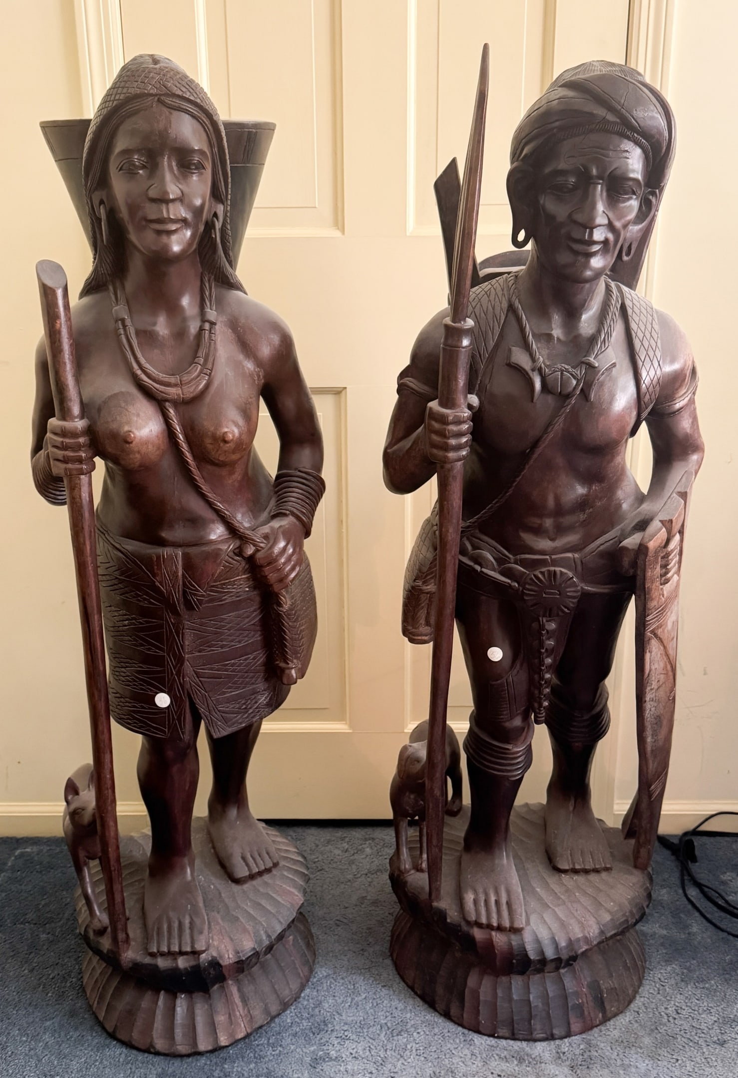 2 Filipino Igorot Carved Wooden Sculptures: Pair of Igorot Tribesmen - Large 4' x 17" x 17", cracks, scuffs, wear and scratches throughout.