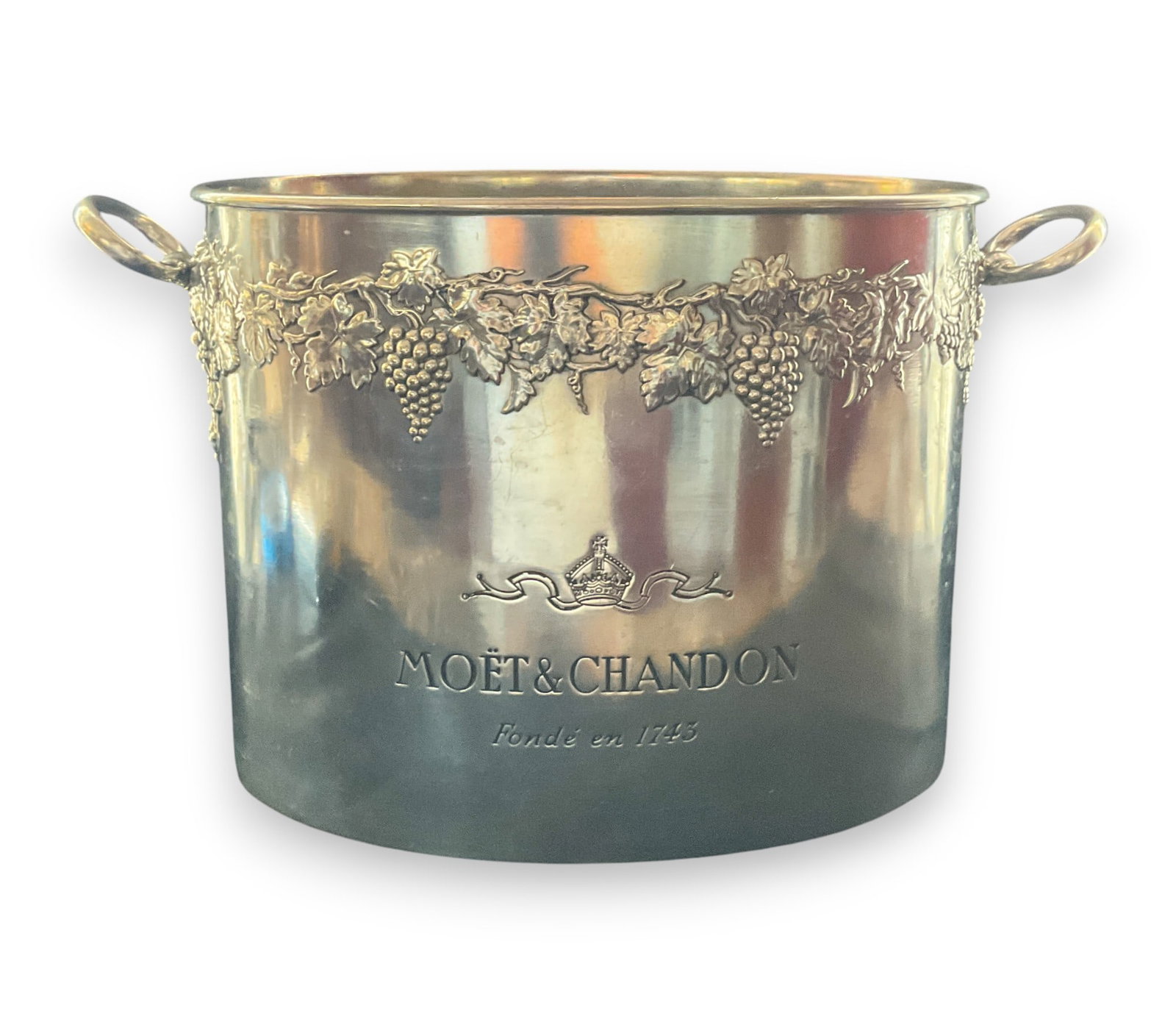 Moet & Chandon France Metal Champagne Ice Bucket: Moet & Chandon metal champagne ice bucket with grape vine motif, inscribed on both sides. Marked made in France. Wear throughout. 9" h x 12" w x 7 1/2" d.