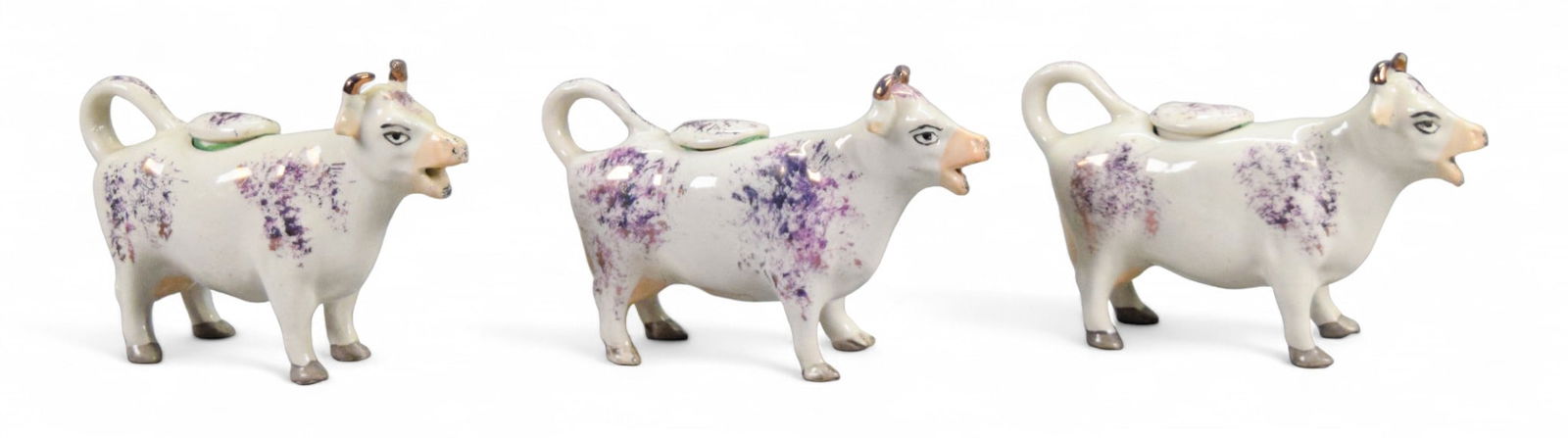3 Staffordshire Pink Lustre Cow Creamers: 3 Staffordshire pottery pink lustre cow creamers. 2 marked England on the undersides, 1 Old Staffordshire Ware England. Each 6 1/2"L x 4 1/4"H. Some crazing, minor paint loss, chip to horn on one.