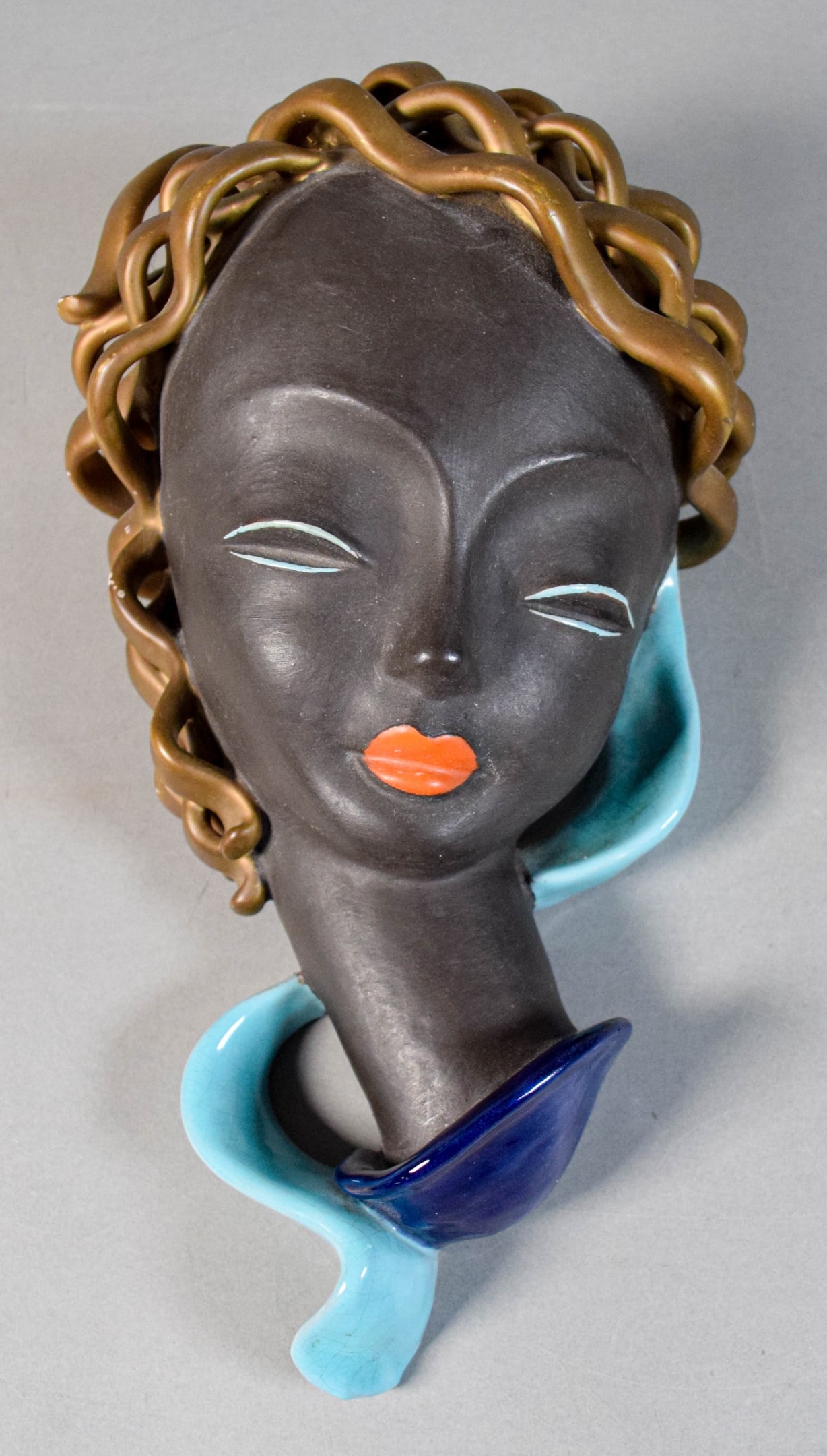 Goldscheider Pottery Wall Mask: Goldscheider pottery wall mask sculpture. Marked Goldscheider Austria and with impressed 7651 on the reverse. 12 1/4"L. Some paint loss to hair.