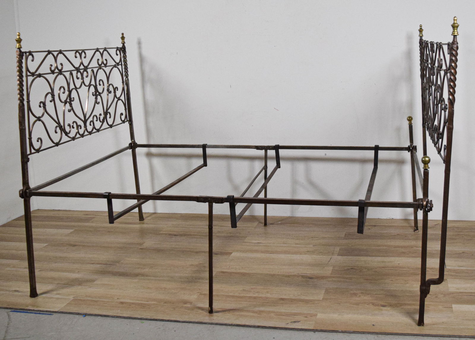 Wrought Iron Campaign Bed: Wrought iron campaign bed. Scrolling headboard and footboard, 14 separate wrought iron pieces. 51 1/2"H x 78 1/2"L x 53 1/2"W as photographed. Missing hardware for center support on one leg.