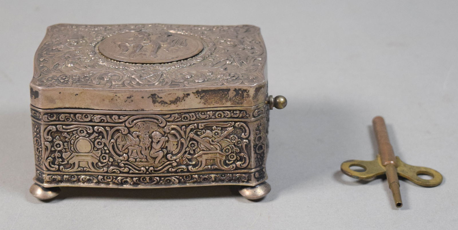 German Sterling Silver Singing Bird Box: German sterling silver singing bird automaton music box. Repousse decoration of cherubs, key wind box with pop-up signing bird. Marked on the underside Sterling Germany. Bird pops-up and moves, but do