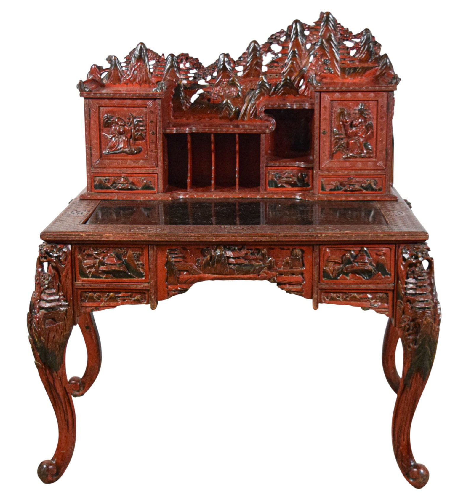 Japanese Carved Red Lacquer Desk: Japanese heavily carved Kamakura-Bori style red lacquer desk. Carved with landscape scenes and scholars. 52 3/4"H x 46"W x 30"D. Scratches, chips and losses to writing surface, wear and losses to lacq