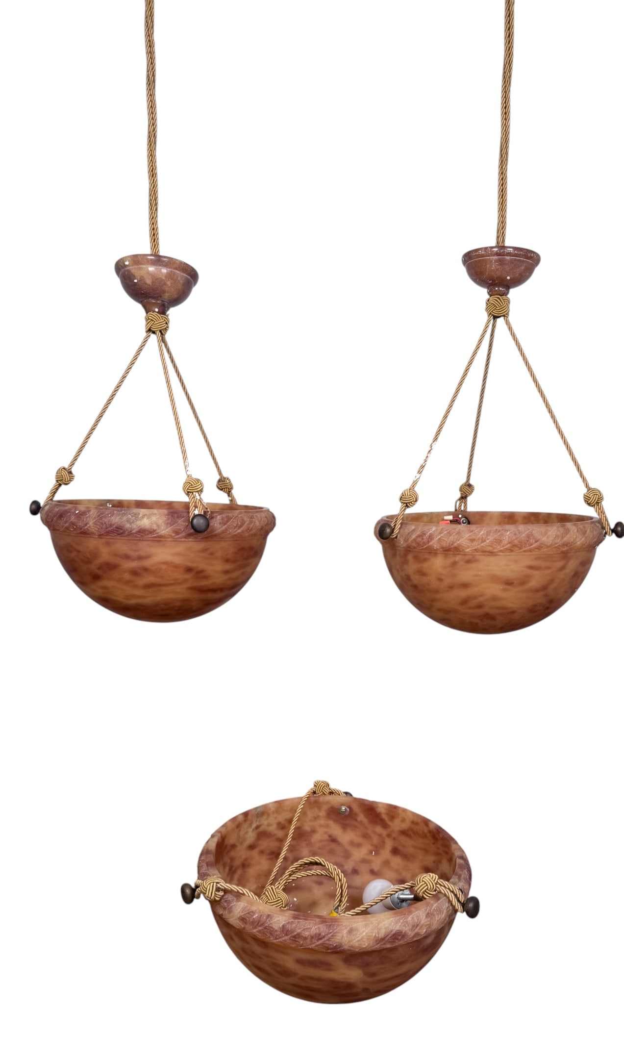 3 Art Deco Carved Alabaster Pendant Light Fixtures: This lot comprises three matching Art Deco style pendant chandeliers, each featuring a hemispherical bowl carved from translucent mottled orange-brown alabaster. The bowls are decorated with a continu