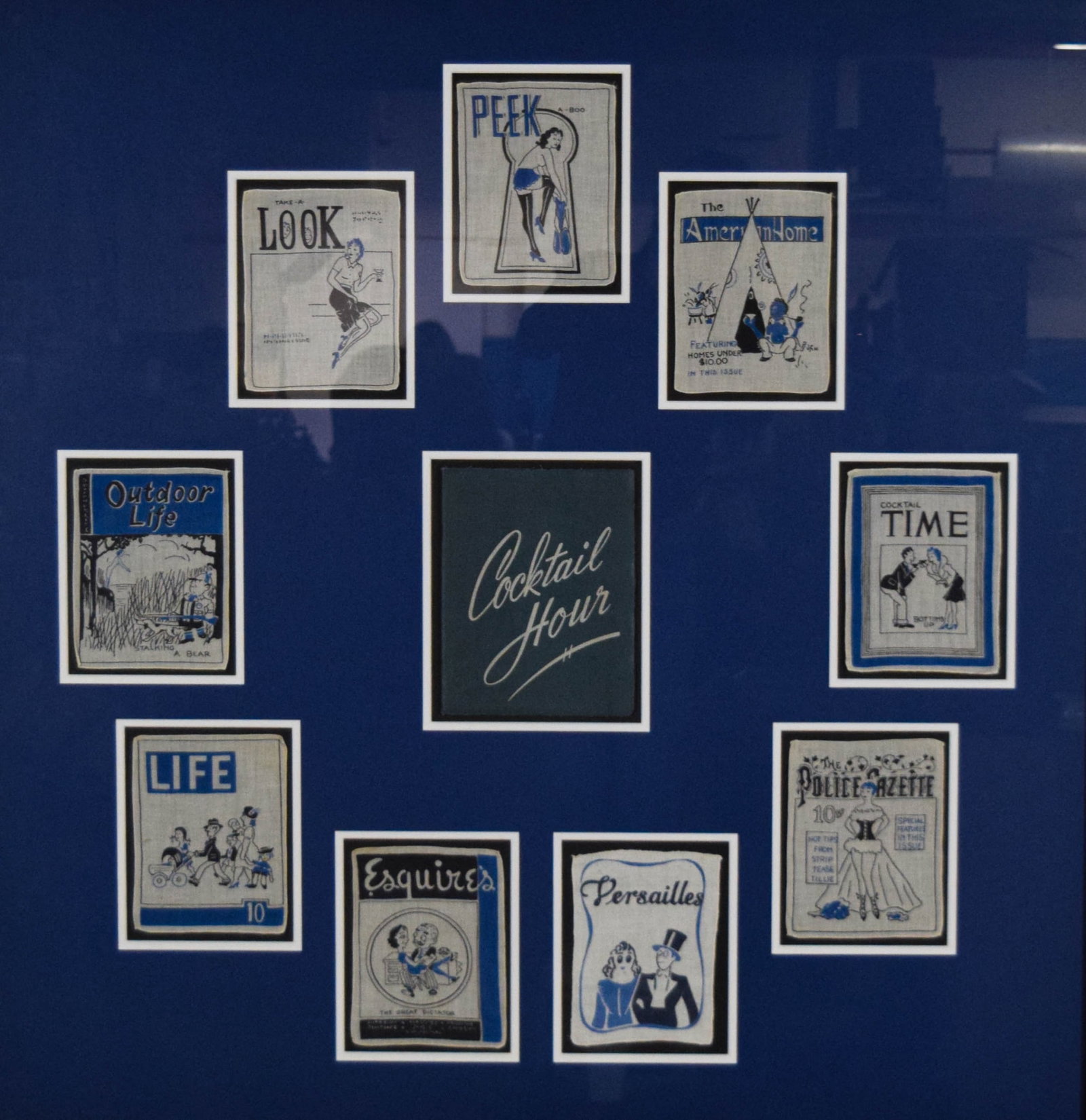 Vintage Satirical Magazine Cover Textile Display: Framed textile display featuring a collection of linen handkerchiefs or cocktail napkins printed with satirical vintage magazine covers. Likely mid-century, with illustrations referencing Life, Esquir