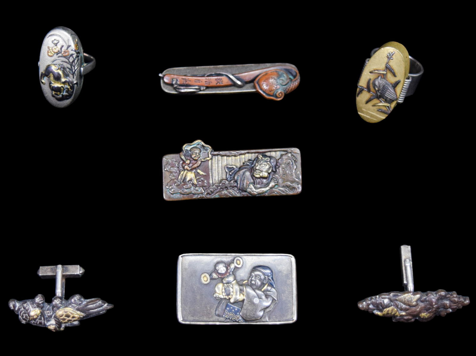 7 Pieces Japanese Sword Silver Jewelry: 7 Japanese sword components mounted as jewelry. Mixed metals with silver mounts. 3 menuki brooches and a pair of menuki cufflinks, 2 kashira rings. 108.3 grams total. Larger menuki brooch 2"L. One bro