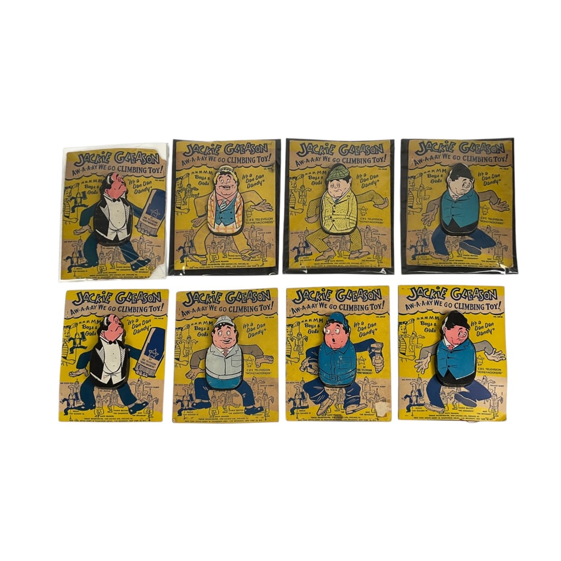 8 Jackie Gleason Show Away We Go Climbing Toys: Group of 8 Jackie Gleason "Aw-a-a-ay We Go" vintage climbing toys in original packaging by Tomar Inc. Plastic hoop and string attached to each figure. Cardstock 8 1/2" H x 6 1/4" W