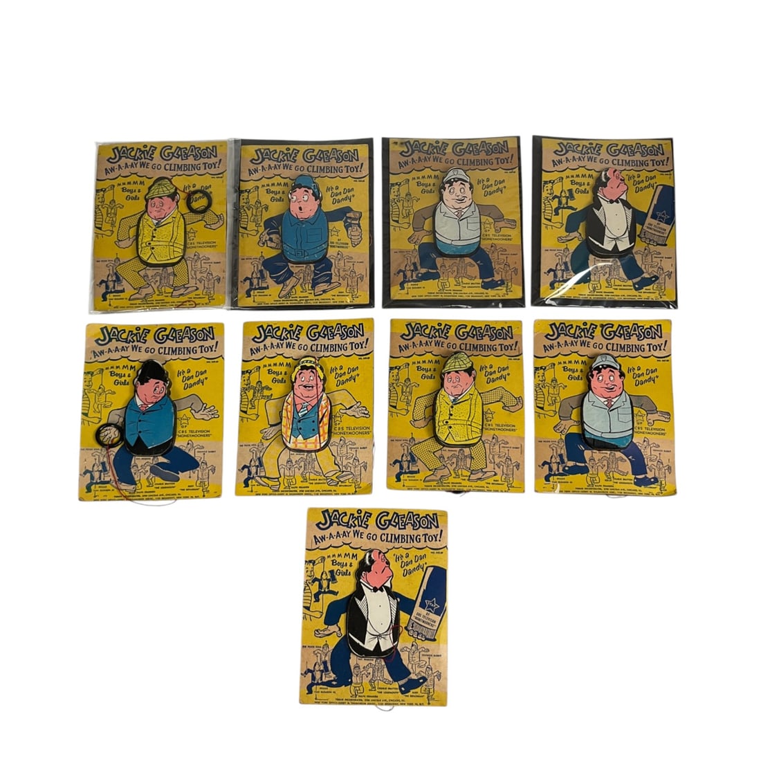 9 Jackie Gleason Show Away We Go Climbing Toys: Group of 9 Jackie Gleason "Aw-a-a-ay We Go" vintage climbing toys in original packaging by Tomar Inc. Plastic hoop and string attached to each figure. Cardstock 8 1/2" H x 6 1/4" W
