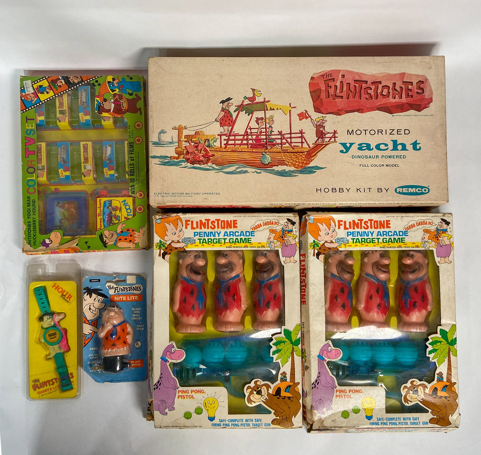 6 Flintstones Toys Incl Remco Yacht Dinosaur Kit 1961-1986: Collection of vintage Flintstones collectible toys including a 1961 Remco Motorized Yacht Dinosaur Powered Hobby Kit with original plastic hull, various components in factory bags, assembly instructio