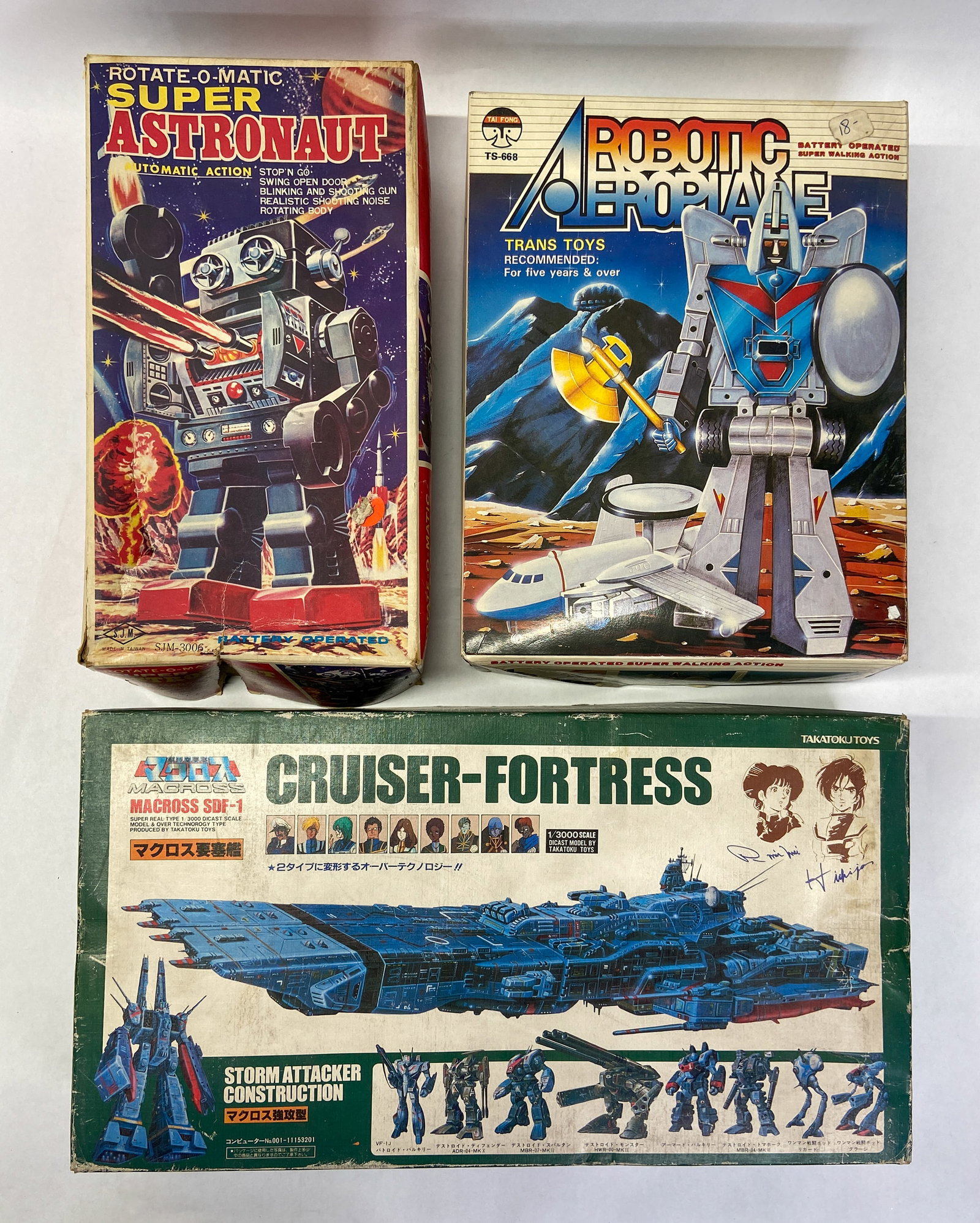 3 Vintage Transformable & Battery-Operated Robots Incl Takatoku Macross c. 1980-1985: Group of three vintage robot toys from the early 1980s. The first item is a Takatoku Toys Macross SDF-1 Cruiser-Fortress (Storm Attacker Construction), a 1/3000 scale transformable model. The second i