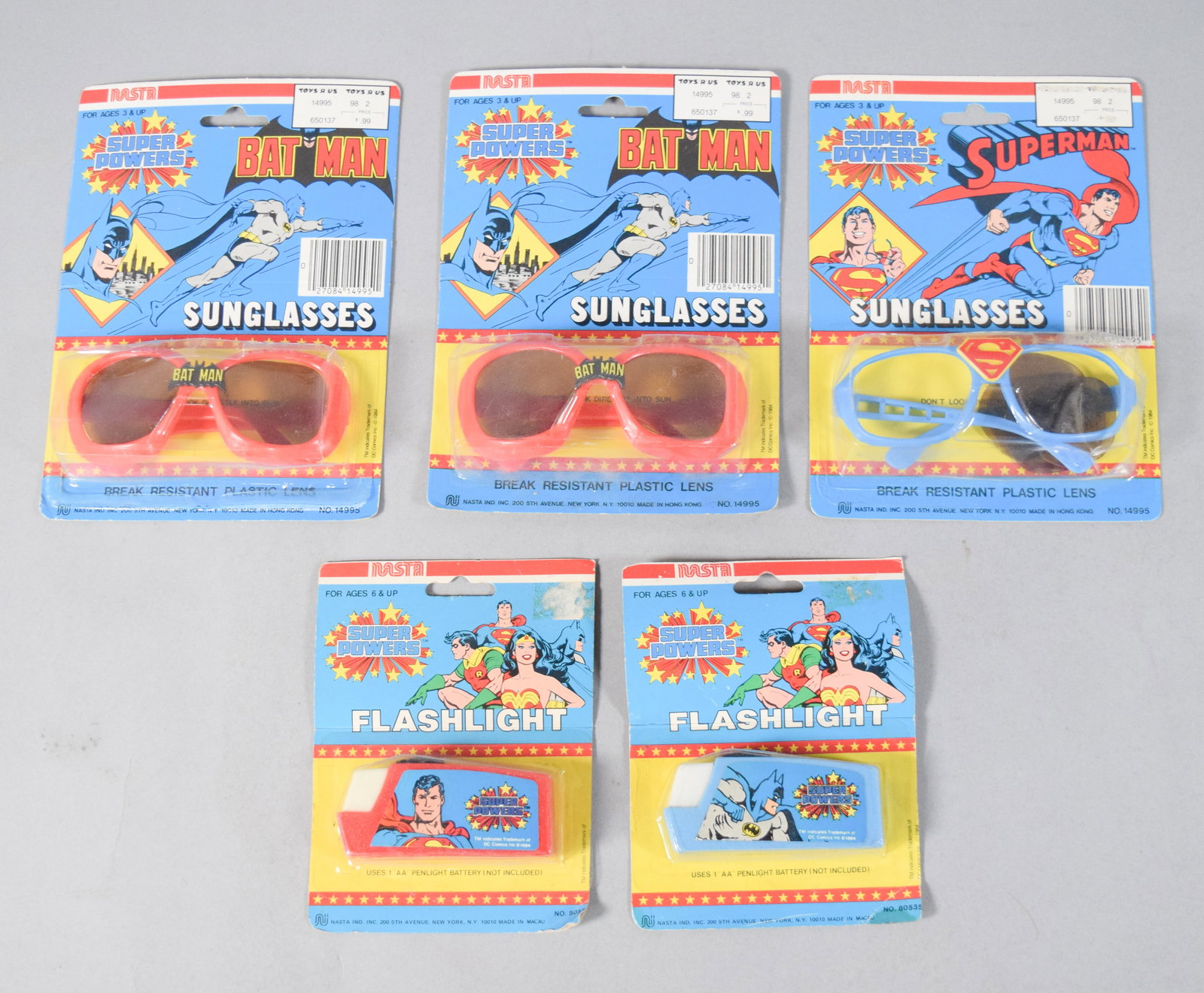 5 DC Nasta Super Powers Sunglasses and Flashlights 1984: Group of five vintage DC Comics Super Powers character merchandise manufactured by Nasta in 1984. Includes three pairs of plastic sunglasses and two penlight flashlights, all preserved in their origin