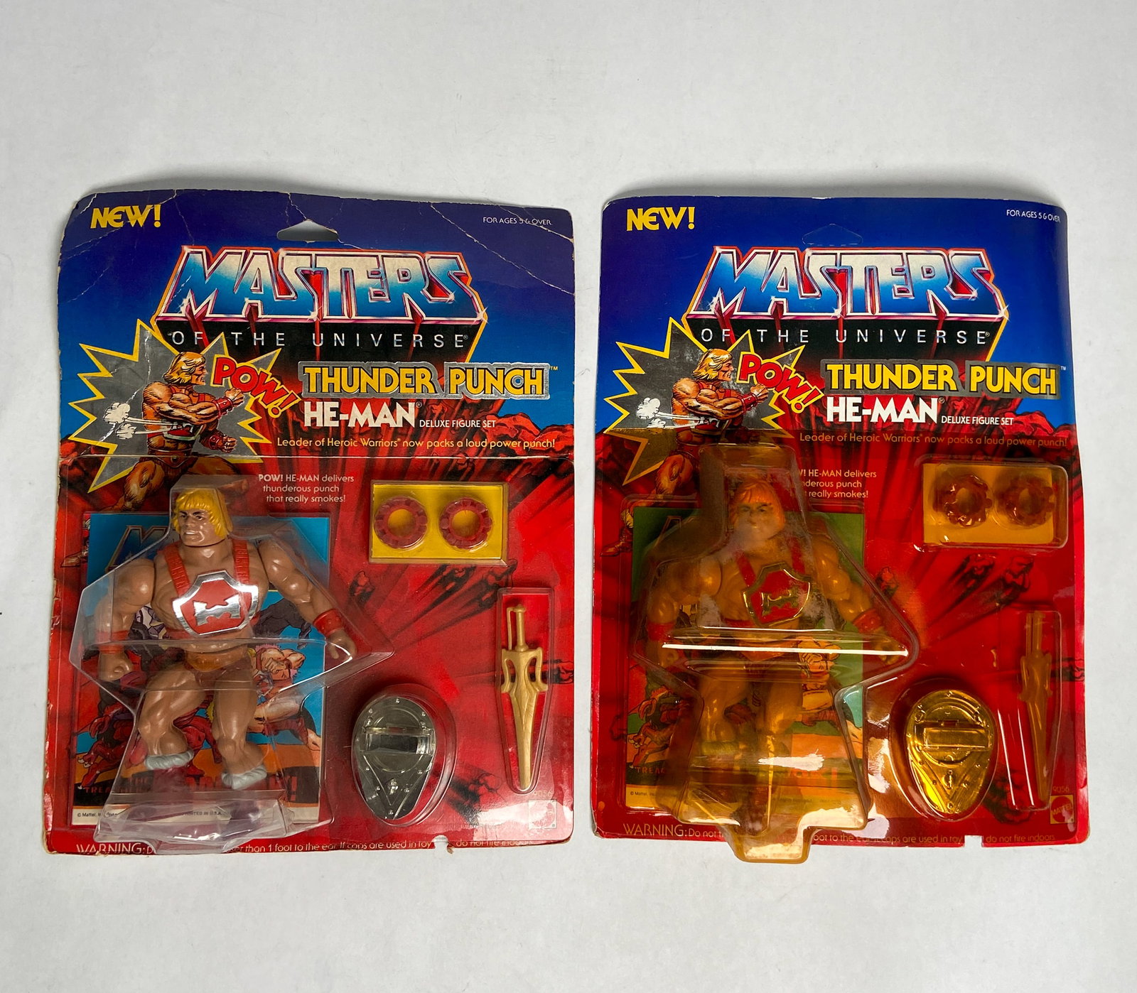 2 Mattel MOTU Thunder Punch He-Man 1984 Deluxe Figure Sets, 1 Unpunched: Two vintage Masters of the Universe "Thunder Punch He-Man" deluxe action figure sets manufactured by Mattel in 1984. The figures are housed in their original blister pack packaging and are accompanied
