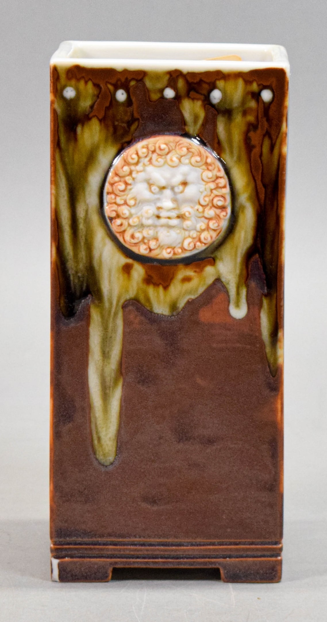 Taxile Doat Porcelain Pate-Sur-Pate Vase: Taxile Maximin Doat (French, 1851-1939) for Sevres. Porcelain vase, drip glaze in browns, pate-sure-pate mythological heads on two sides. Signed Doat Sevres on the underside. 7 5/8" H x 3 1/4" W x 3"