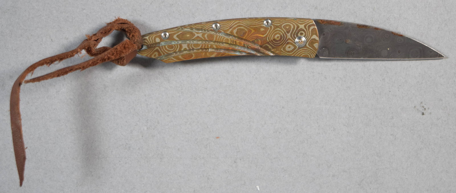 William Henry Model 5827 Mokume Gane Folding Pocket Knife: Mokume Gane folding pocket knife, model number 5827, by William Henry. Blade constructed of pattern-welded Damascus steel with a Mokume Gane handle. Blade marked WH. 4 1/2" L, open.