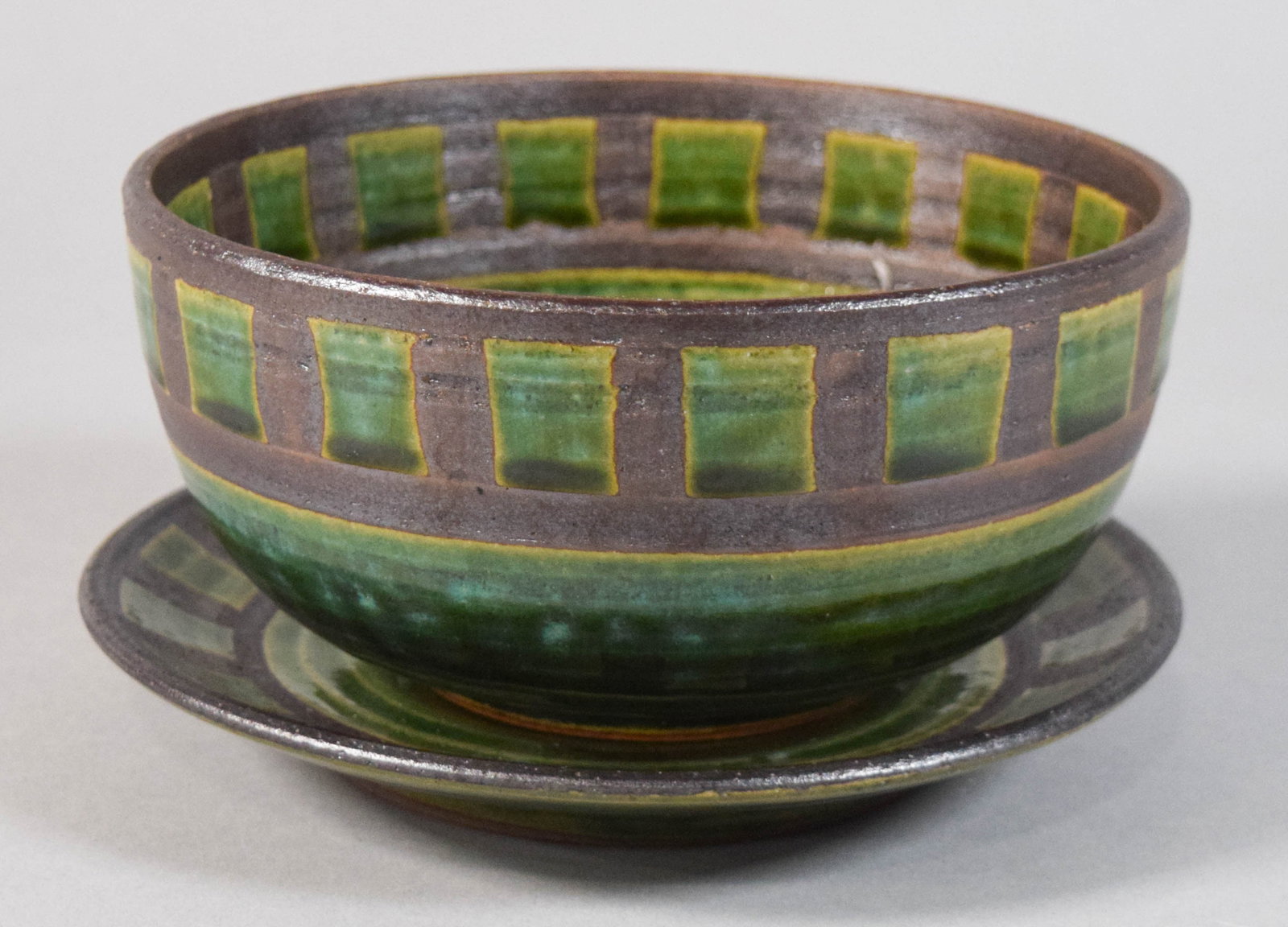 Oribe Style Ceramic Bowl and Underplate by Masayama: Ceramic bowl and underplate by Masayama decorated in the Japanese Oribe style. Dark brown semi-matte glaze and translucent green glaze. Each piece marked on the underside. 4 1/4" H x 7" diameter.