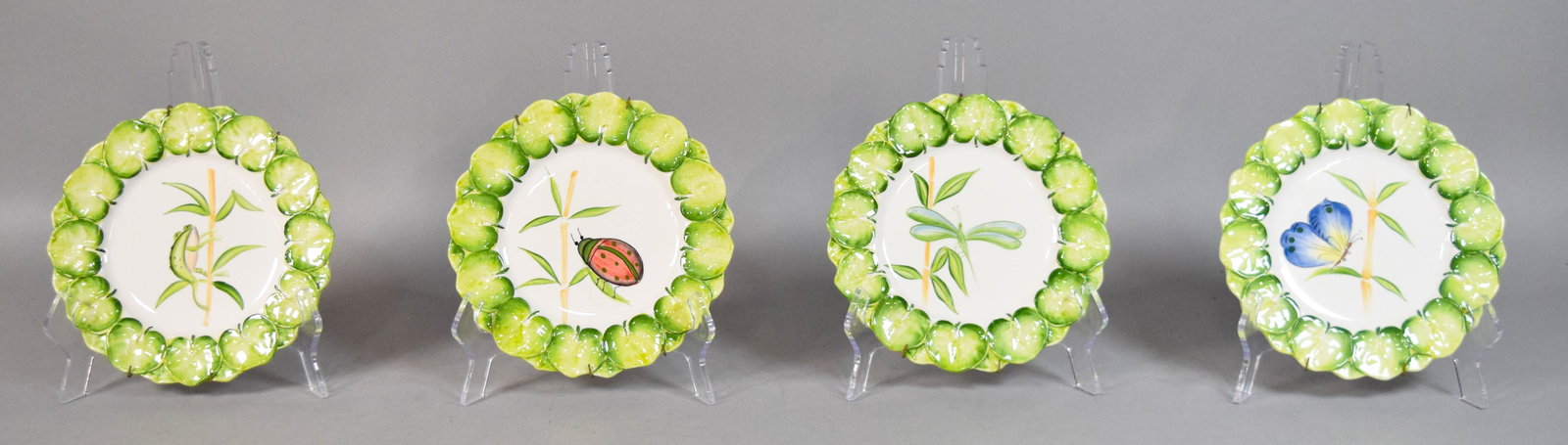Set of Four Intrada Italian Ceramic Decorative Plates: Set of four Intrada ceramic decorative plates. White glazed centers hand-painted with various motifs. Fitted with metal spring-style wall hangers. Marked Intrada Made in Italy on the reverse. 8 1/2" d