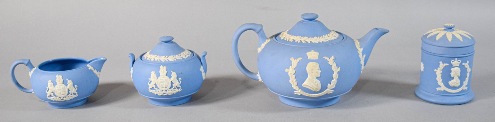 4 Piece Wedgwood Jasperware 1953 Coronation Commemorative Set: Four pieces of Wedgwood blue jasperware commemorative items manufactured for the 1953 coronation of Queen Elizabeth II. Teapot with lid, lidded sugar bowl, creamer, and lidded jar. Each with glazed co