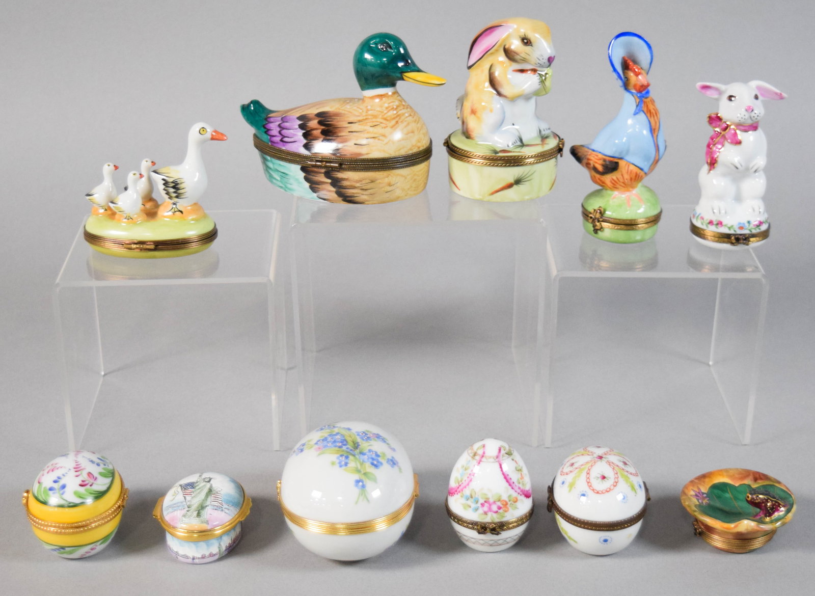 Group of 11 Porcelain and Enamel Trinket Boxes Incl Limoges and Halcyon Days for Tiffany: Group of 11 hand-painted porcelain and enamel trinket boxes. Includes several Limoges porcelain boxes, four egg-shaped boxes, a circular enamel-on-copper musical box by Halcyon Days for Tiffany & 
