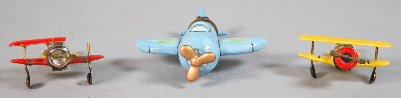 3 Limoges Airplane Trinket Boxes: Three hand-painted Limoges porcelain miniature airplane trinket boxes. Two biplanes and one monoplane. Underside marked Peint Main, Limoges France, Chamille. 1 1/4 x 3 1/2 inches.