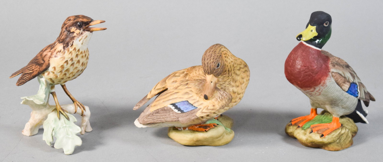 Trio of Goebel and Boehm Porcelain Bird Figurines: Group of three hand-painted porcelain bird figurines including a pair of mallard ducks and a songbird. Songbird marked Goebel, W. Germany. Mallard pair marked Boehm, Made in USA. Largest piece 6 1/2" 