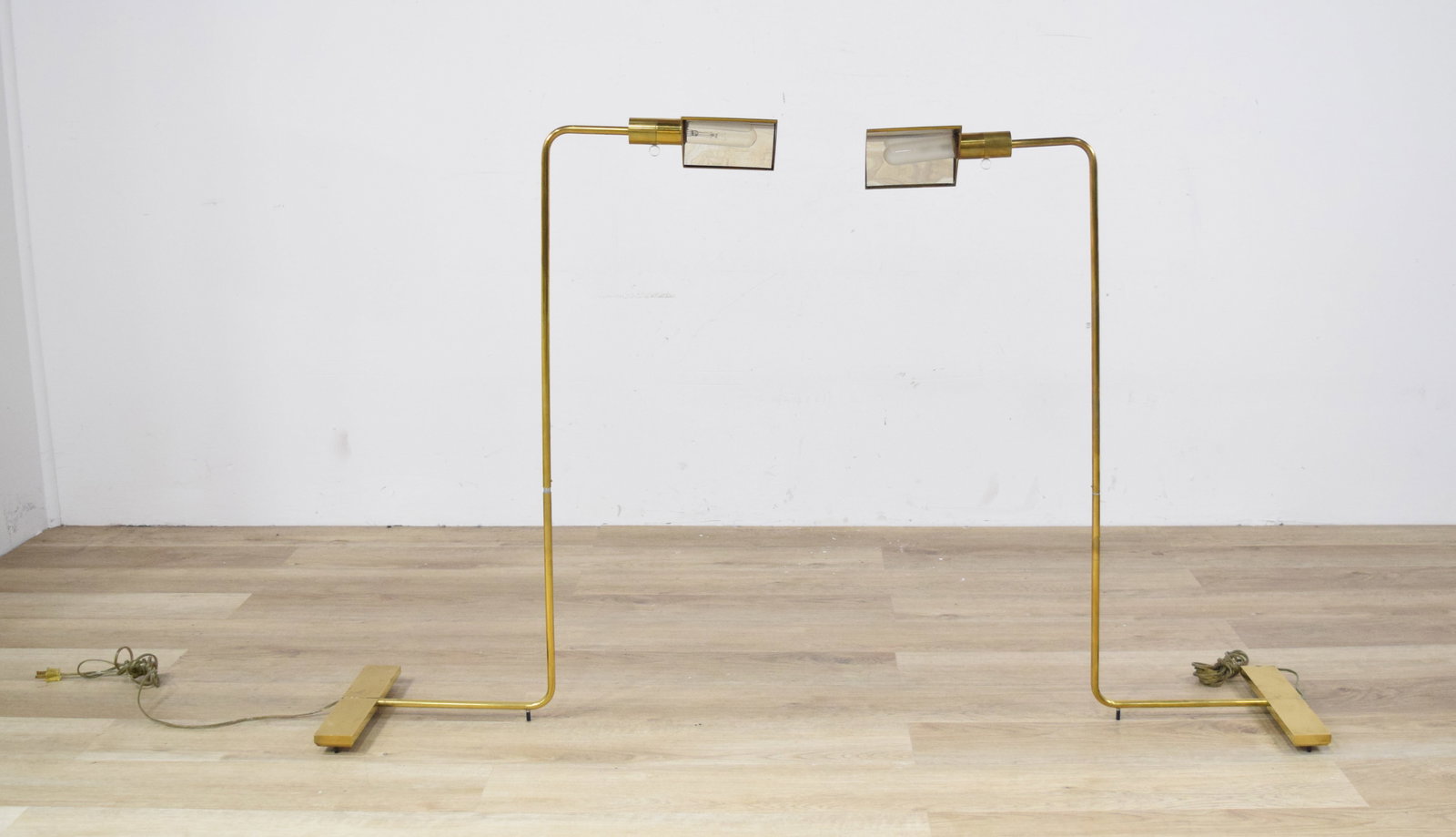 Pair of MCM Brass Floor Lamps Attributed to Cedric Hartman: Pair of Mid-Century Modern floor lamps attributed to Cedric Hartman (American, b. 1929). Brass and mirrored metal on weighted T-shaped bases. Each stem bends at ninety-degree angles to form a low-prof