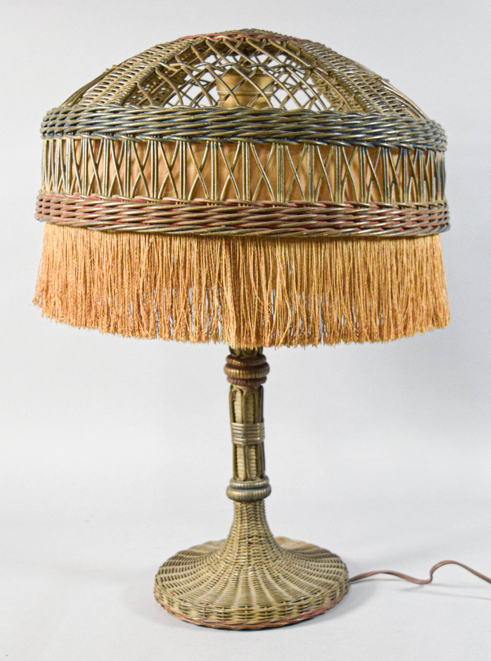 Stickley Style Woven Wicker Table Lamp: Stickley style woven wicker table lamp with fringed shade. Flared circular base and finely woven reeded stem. Matching domed wicker shade with an open-work lattice top. Interior shade lined with fring