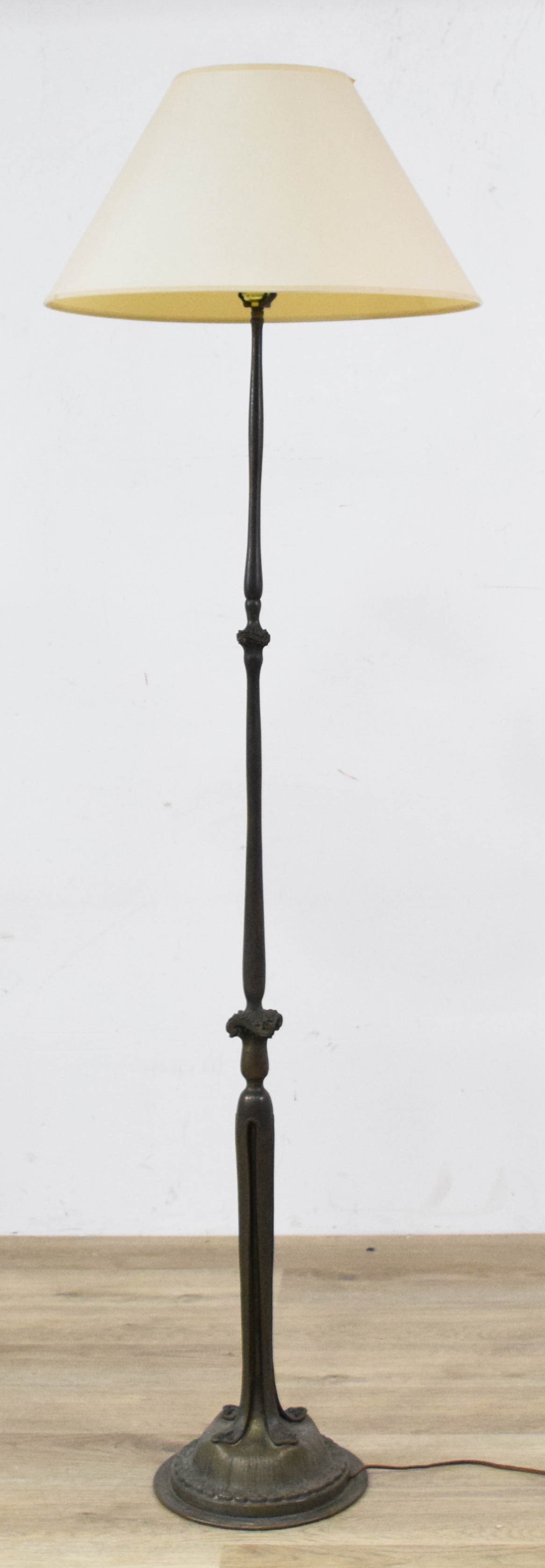 Tiffany Style Patinated Bronze Floor Lamp: Tiffany style patinated bronze floor lamp with off-white fabric shade. 20th century. Tested and working. 67" H x 20" shade diameter. 11" base diameter.