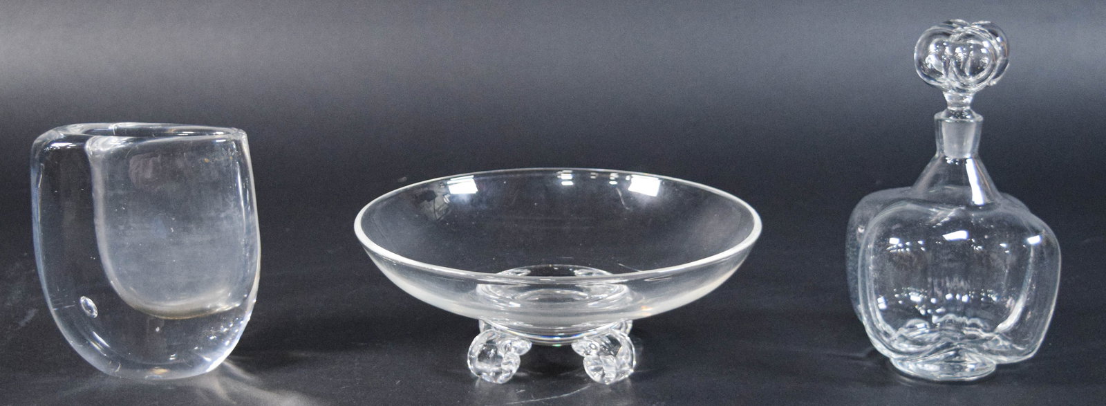 Group of 3 Steuben and Kosta Art Glass Pieces: Group of three Steuben and Kosta art glass pieces. The first is a Kosta Festa vase designed by Vicke Lindstrand, featuring a heavy, thick-walled form with an asymmetrical rim and controlled bubble inc