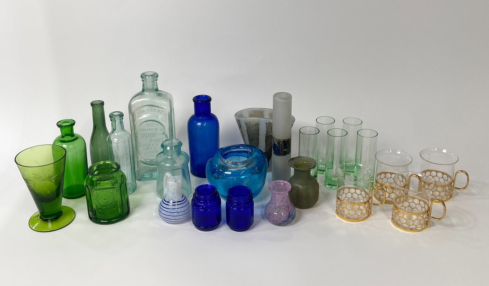 25 Decorative Glass Vessels Incl Kosta Boda: Collection of 25 assorted glass vessels including art glass, antique apothecary bottles, and mid-century decorative items and barware. Featured art glass includes a small Kosta Boda vase designed by B
