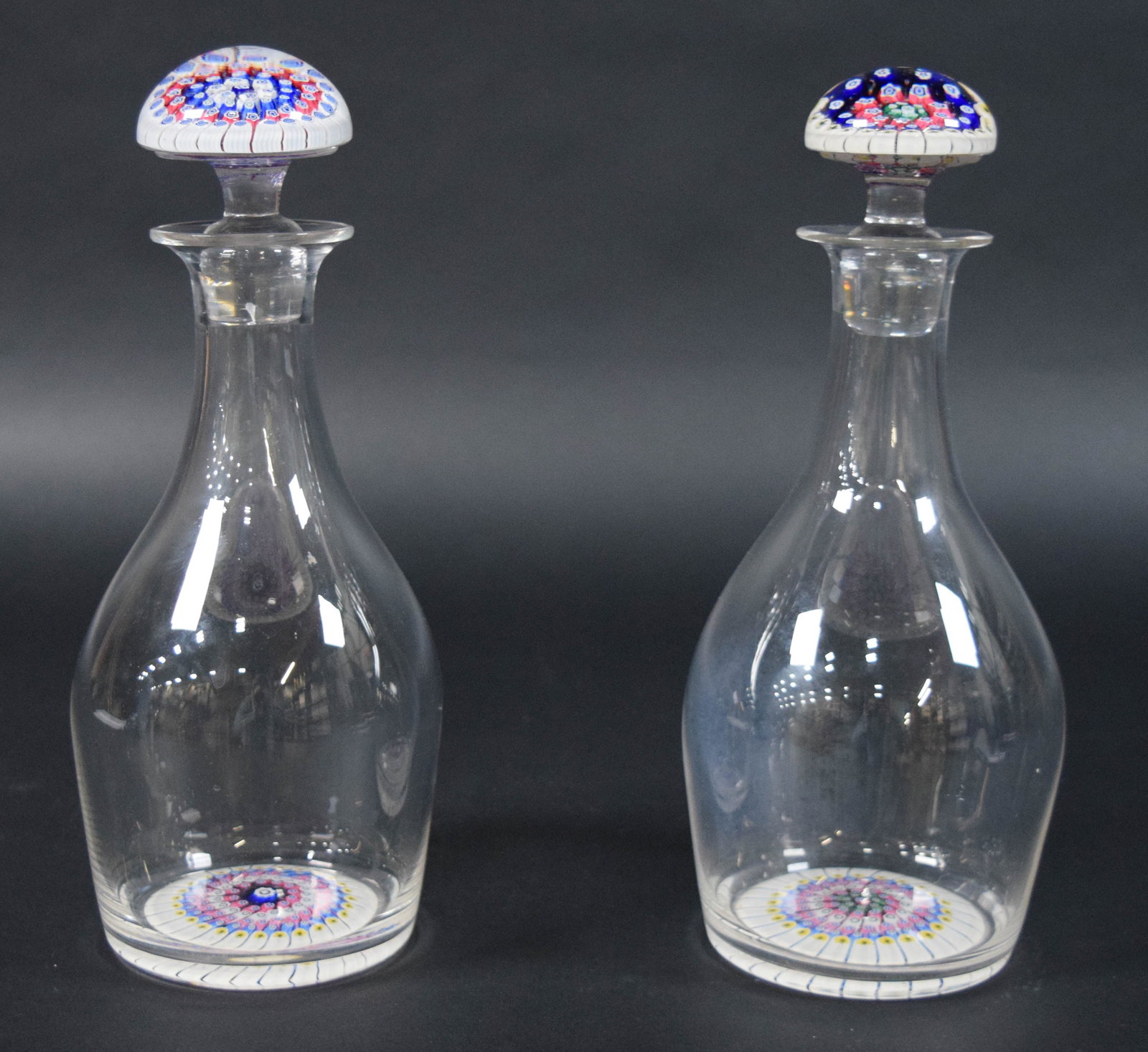 Pair of Venetian Style Millefiori Glass Decanters: Pair of Venetian style millefiori glass decanters with matching stoppers. Each vessel is decorated with an integrated millefiori glass disk at the base and a corresponding domed millefiori glass stopp
