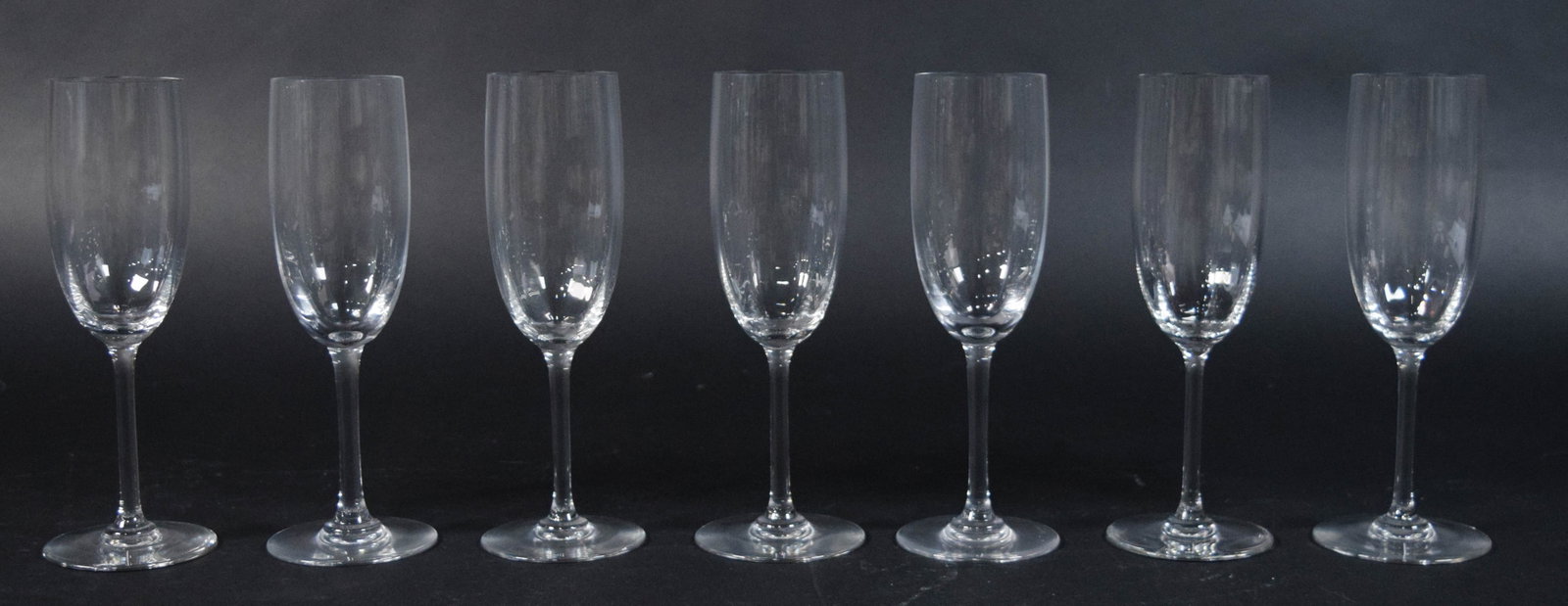 Set of 7 Baccarat Perfection Crystal Champagne Flutes: Set of seven Baccarat clear lead crystal champagne flutes in the Perfection pattern. Each glass with a tall, cylindrical bowl with a rounded base, a long slender stem, and a flat circular foot. Each s
