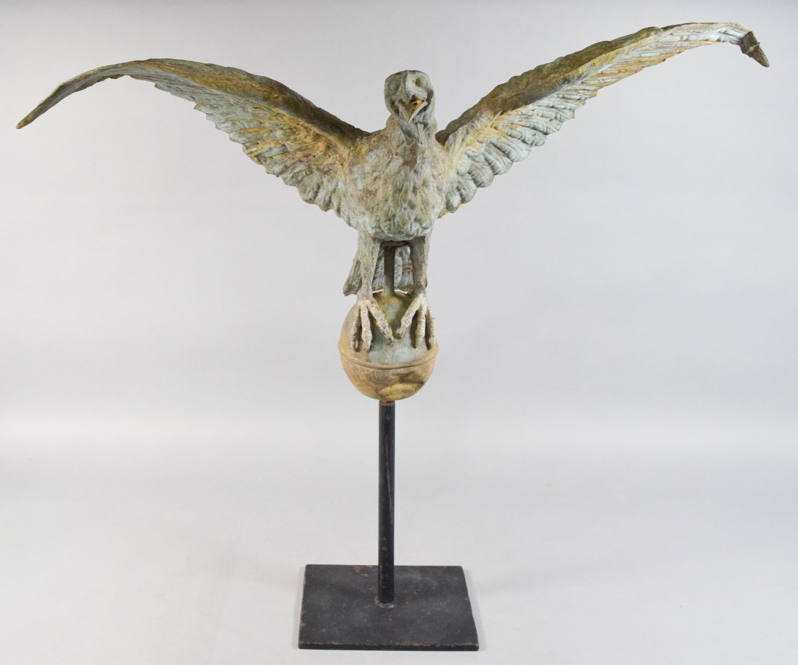 American Copper Eagle Weathervane Topper on Stand: American molded copper eagle on a display stand, designed as a weathervane topper. Constructed with hollow-formed copper sheets. Surface exhibits a weathered verdigris patina with significant remains 