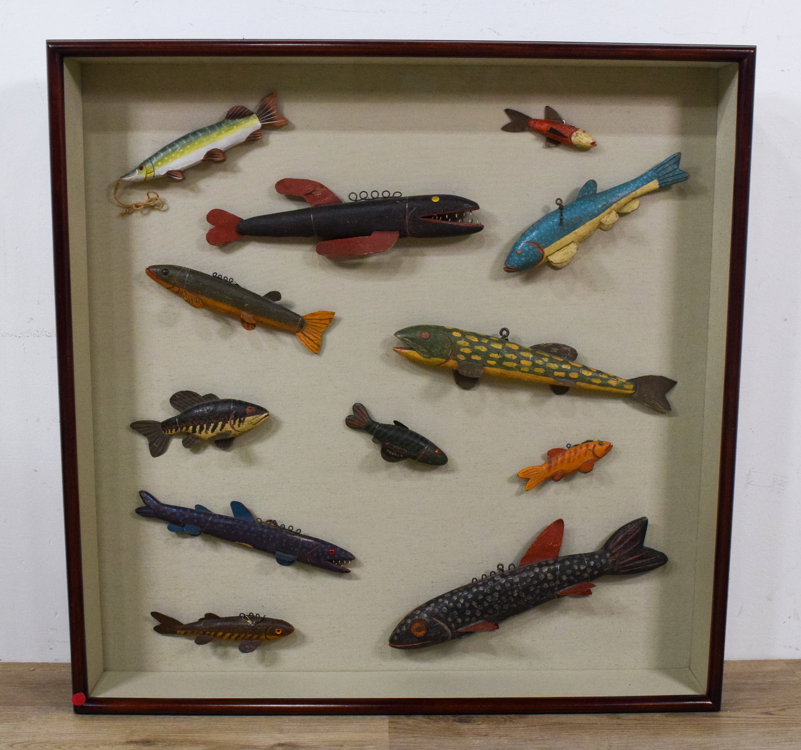 Collection of 12 Folk Art Fish Decoys by Swenarton: Collection of 12 hand-carved and painted wooden fish decoys in a shadowbox. Wooden bodies, metal fins, and wire loops for suspension. Several signed Gordon Swenarton 1992. 35 1/2" H x 35 1/2" W x 5" D