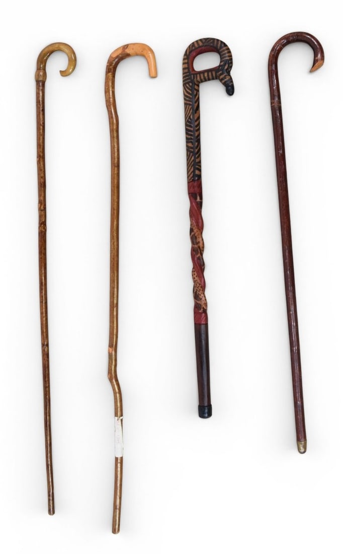 Group of 4 Wooden Walking Sticks and Canes: Group of four wooden walking sticks and canes. The collection includes several natural wood canes with crook handles, exhibiting organic textures, wood knots, and varied finishes. One decorative piece